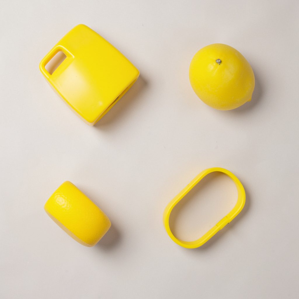 Overhead flat-lay photograph of an open instruction booklet and a smartphone resting on a clean white surface, photographed from directly above with neutral light and a single yellow accent marker.