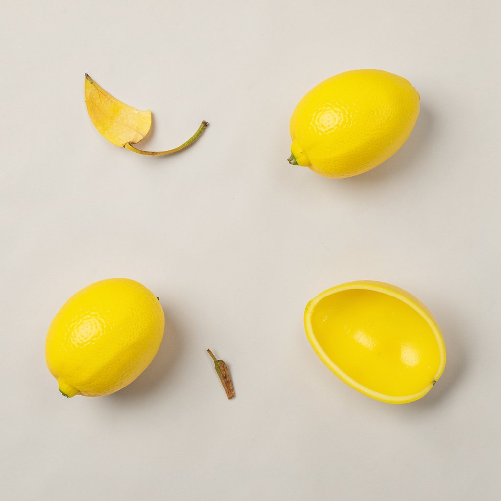Overhead flat-lay photograph of a hand placing a smartphone onto a workbench scattered with small tools, photographed from above with high-contrast black and white tones accented by safety yellow.